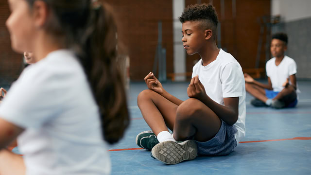 African American boy meditating during a group yoga session.