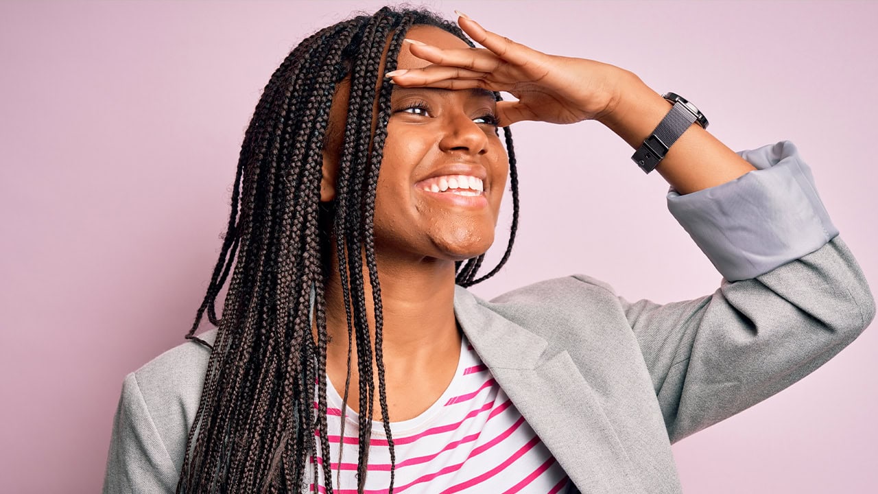 African American businesswoman looking into the distance while standing in front of a pink color background. Image produced by More Jersey.