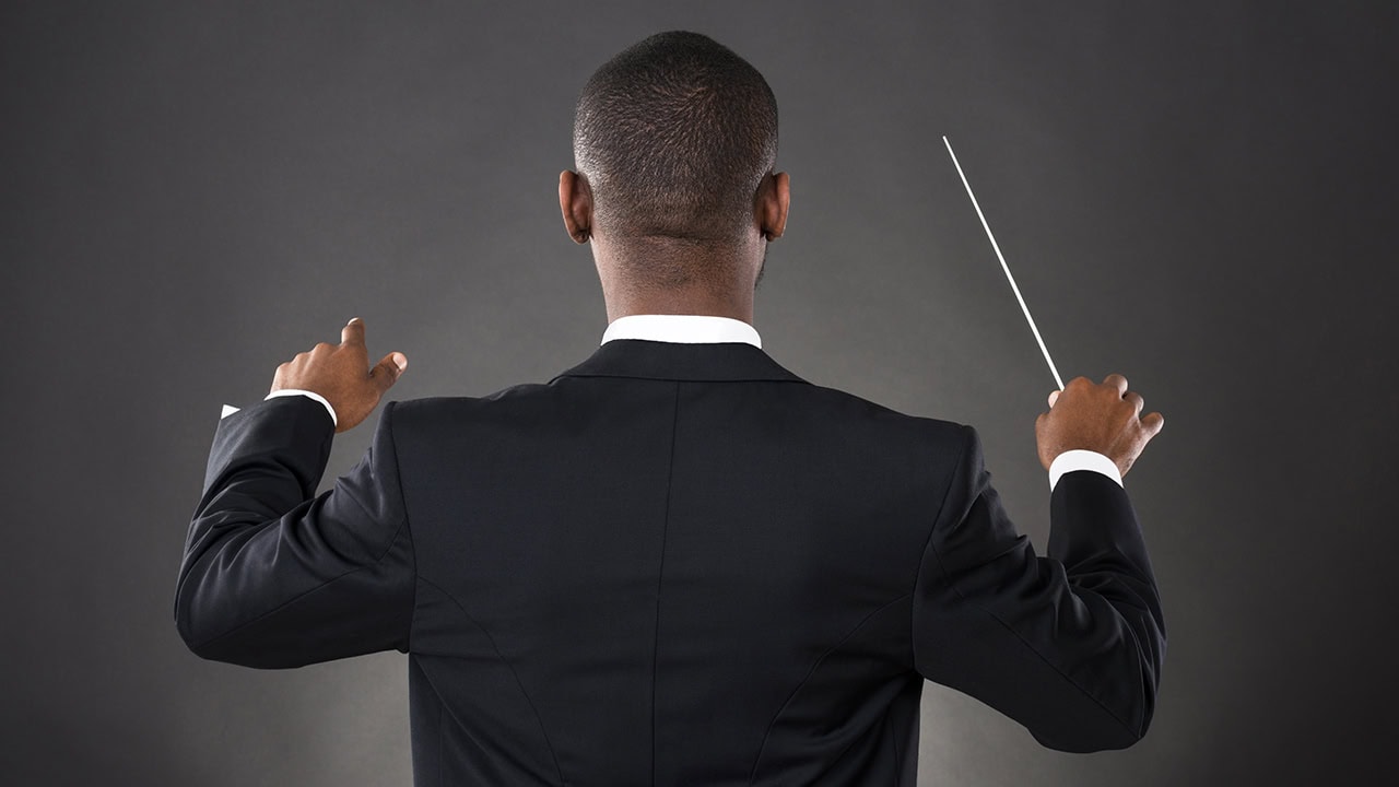 African American conductor directing an orchestra. Image produced by More Jersey.