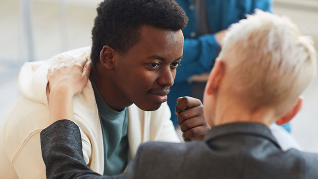 African-American male receiving comfort from a psychologist during a support group session.