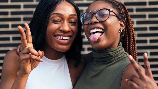 African American teenagers posing for camera displaying peace fingers.