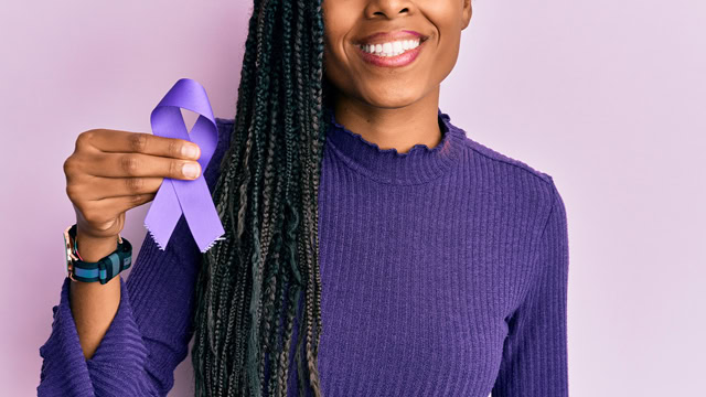 African American woman holding a purple ribbon for cancer and epilepsy awareness.