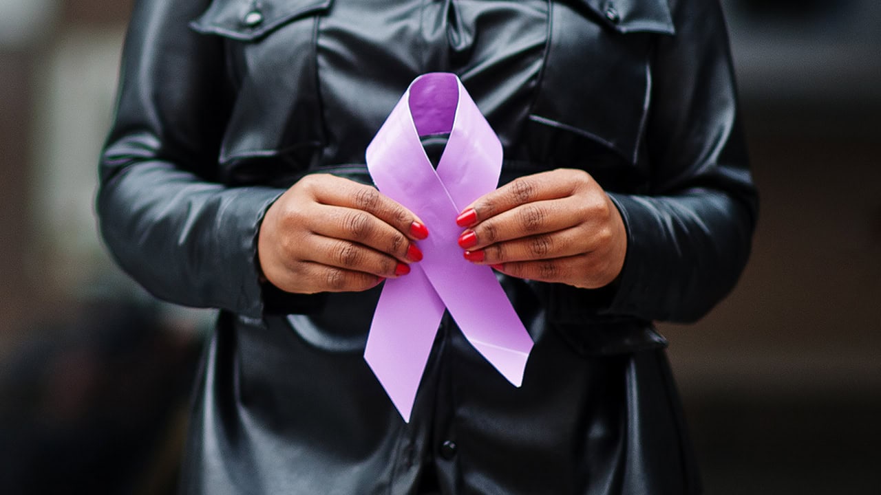 African American woman holding purple ribbon at New Jersey domestic violence awareness event. Image produced by More Jersey.