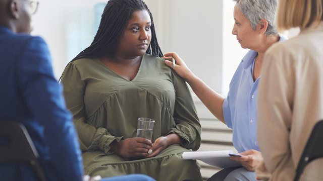 African-American woman listening to psychologist during support group meeting.