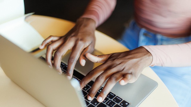 African American woman typing on a laptop.