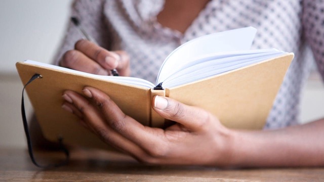 African-American woman writing in her journal at New Jersey writing workshop.