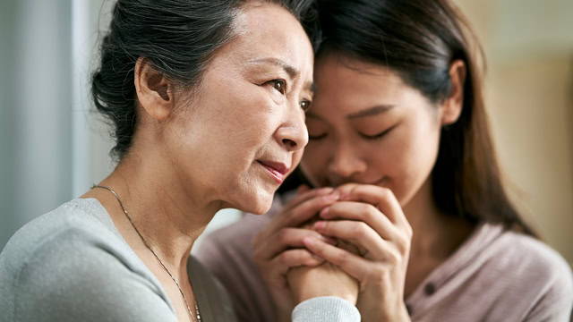 Asian daughter comforting her senior mother.