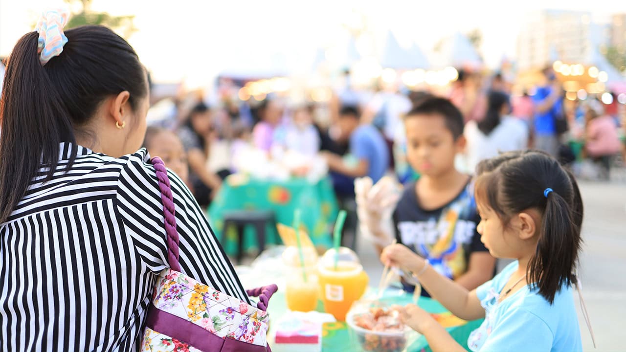 Asian family sitting and eating at New Jersey food festival. Image produced by More Jersey.
