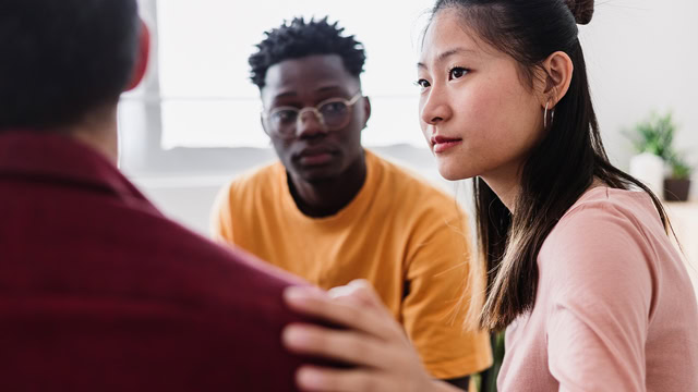 Asian woman comforting a fellow resident during a group therapy session.