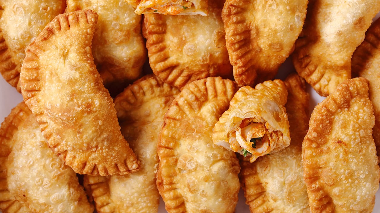 Assortment of deep fried empanadas on white paper. Image produced by More Jersey.