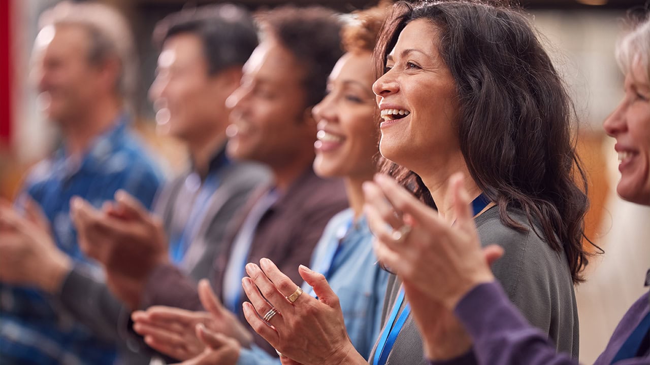 Audience of business executives applauding during a presentation at a New Jersey conference. Image produced by More Jersey.