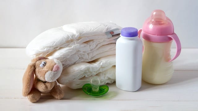 Baby supplies: diapers, pacifier, bunny toy, and feeding bottle.