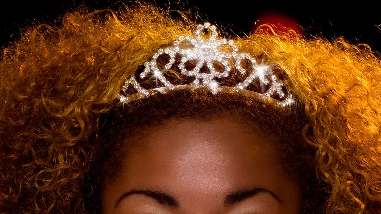 Black New Jersey woman wearing a tiara with natural curly brown hair. Image produced by More Jersey.