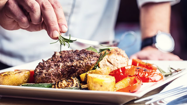 Chef plating beef steak dinner with vegetables at New Jersey restaurant.