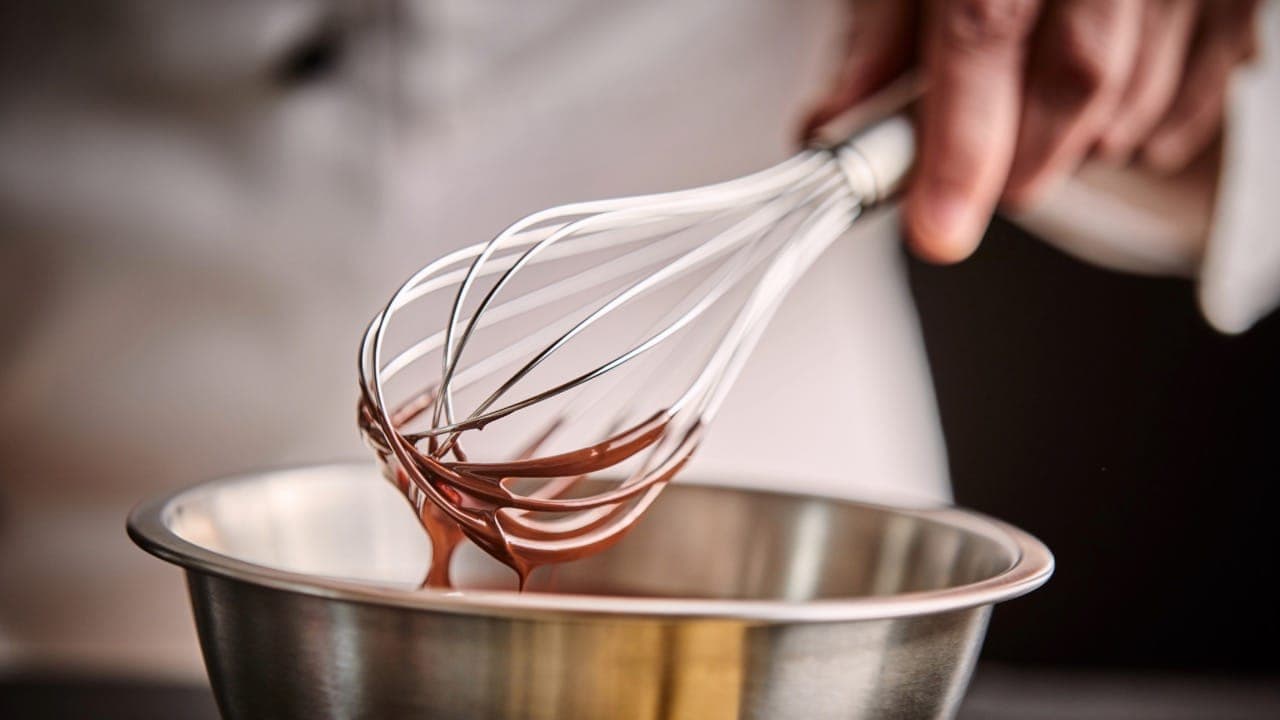 Chef preparing melted chocolate in a mixing bowl at New Jersey cooking and baking class.