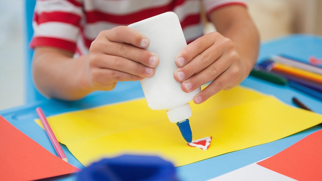 Child squeezing glue onto paper at New Jersey craft event.