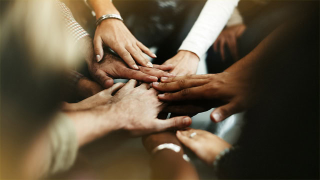 Close-up of a diverse group of resident joining hands in a pile.