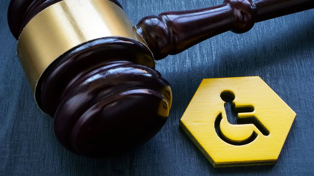 Close-up of a gavel and handicapped person sign.