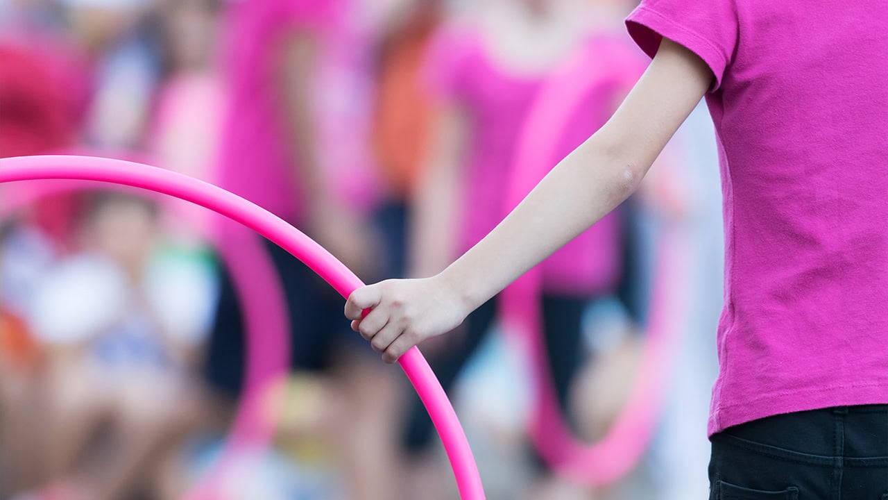 Close-up of a young girl preparing for hula hoop exercises at school. Image produced by More Jersey.