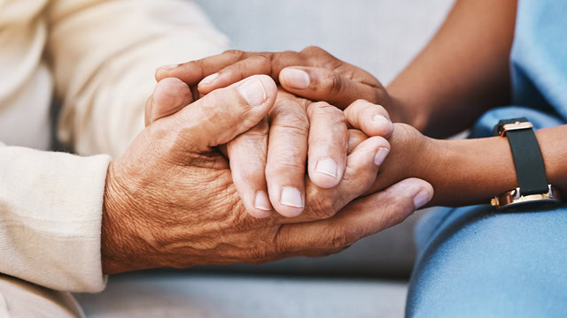 Close-up of an African American caregiver comforting a white senior.