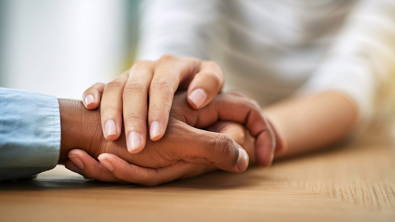 Close-up of an African American couple holding hands as a sign of support.