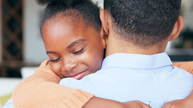 Close-up of an African American daughter and father hugging each other.