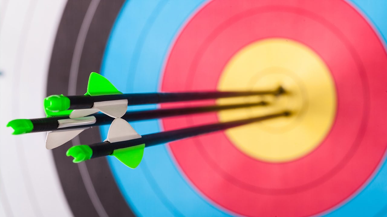 Close-up of archery target with three arrows striking the bullseye at New Jersey archery venue.