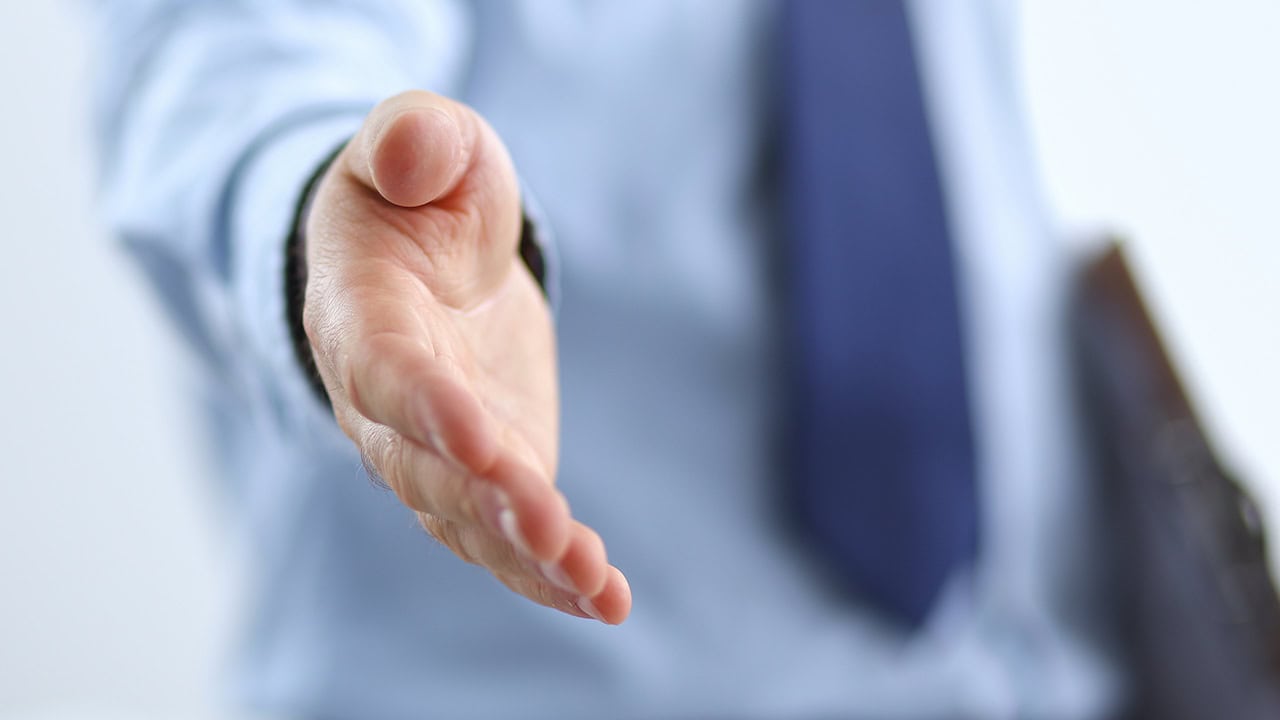Close-up of person extending their hand for a handshake.