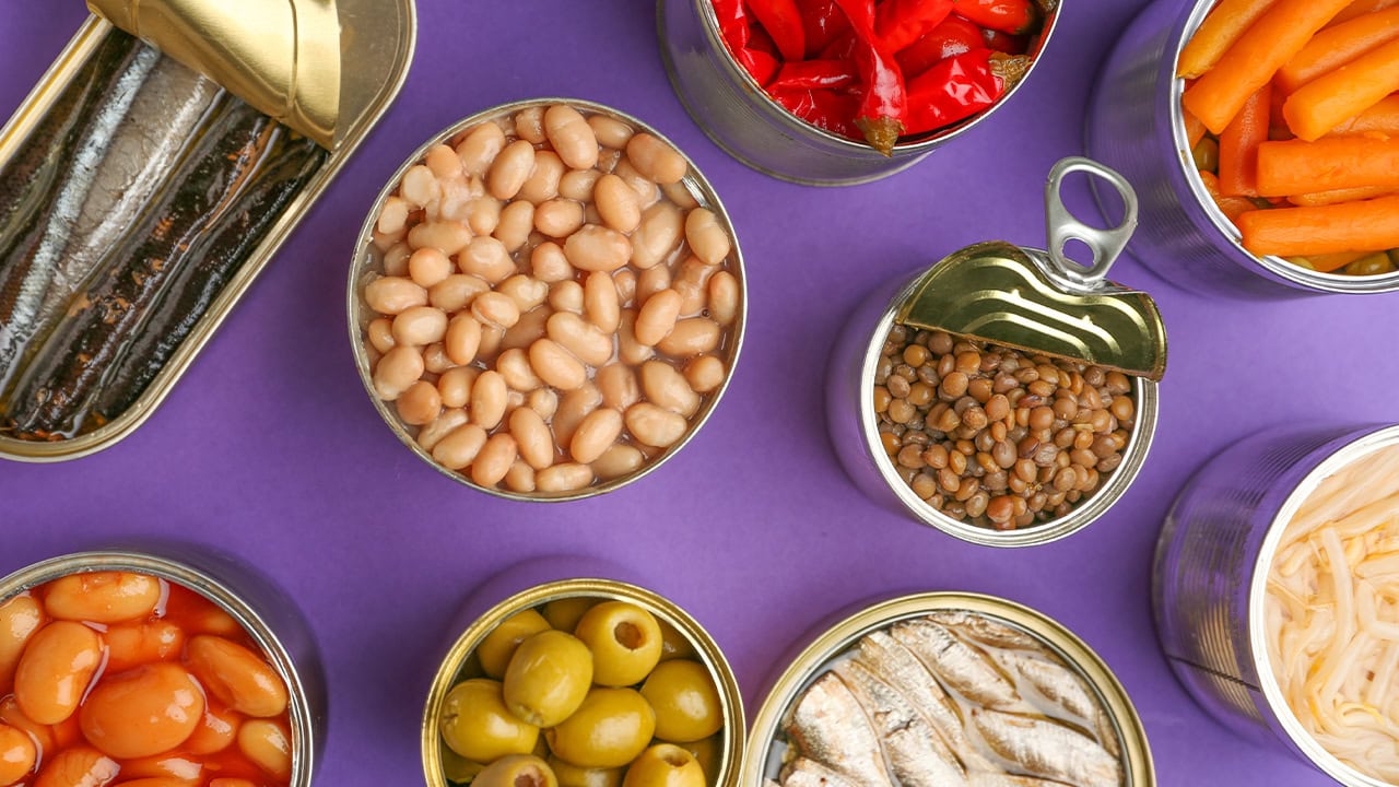 Close-up of various canned foods on a purple color background. Image produced by More Jersey.