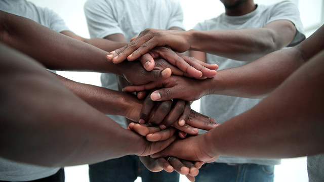 Close-up of young African American males stacking their hands in a hand pile.