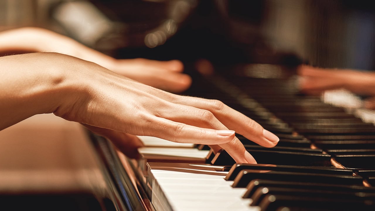 Close up view of female hands playing the piano.