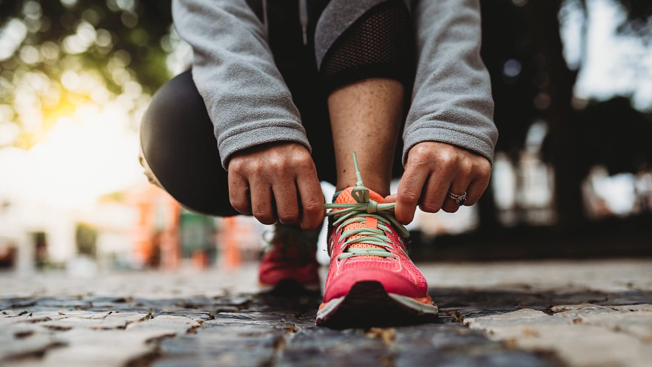 Closeup of a New Jersey woman tying her shoelace before an outdoor workout.