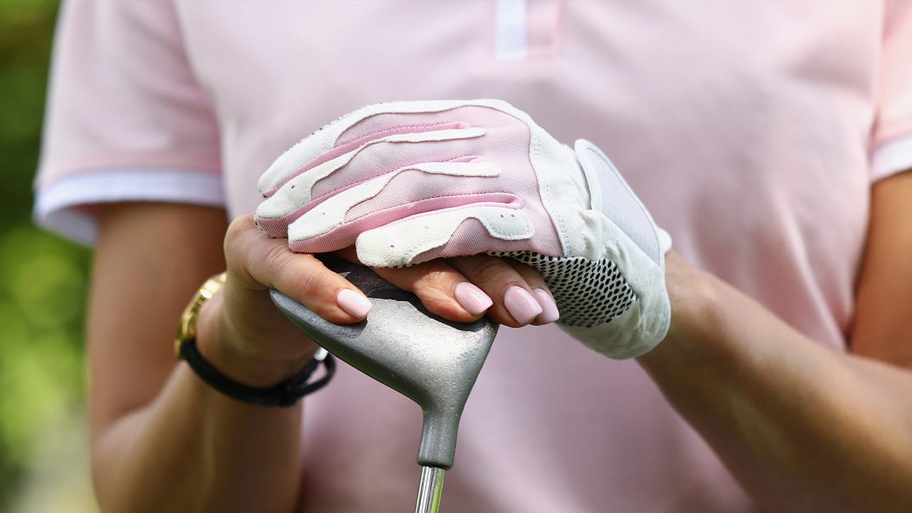 Closeup of New Jersey female golfer wearing a light pink shirt and matching gloves.