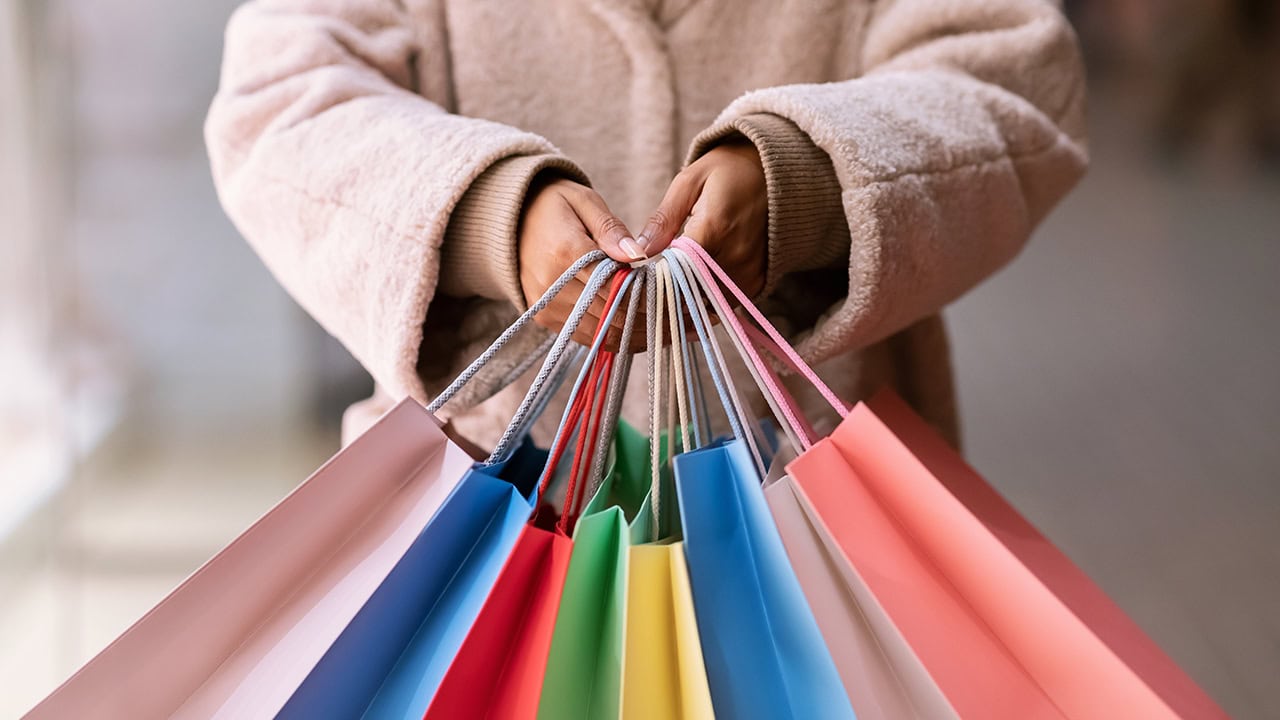 Close-up of woman holding many bags from holiday marketplace shopping. Image produced by More Jersey.