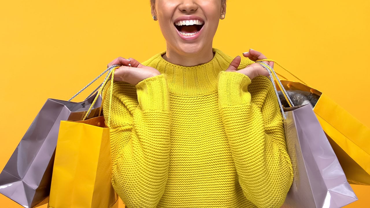 Excited woman holding multiple bags from shopping. Image produced by More Jersey.