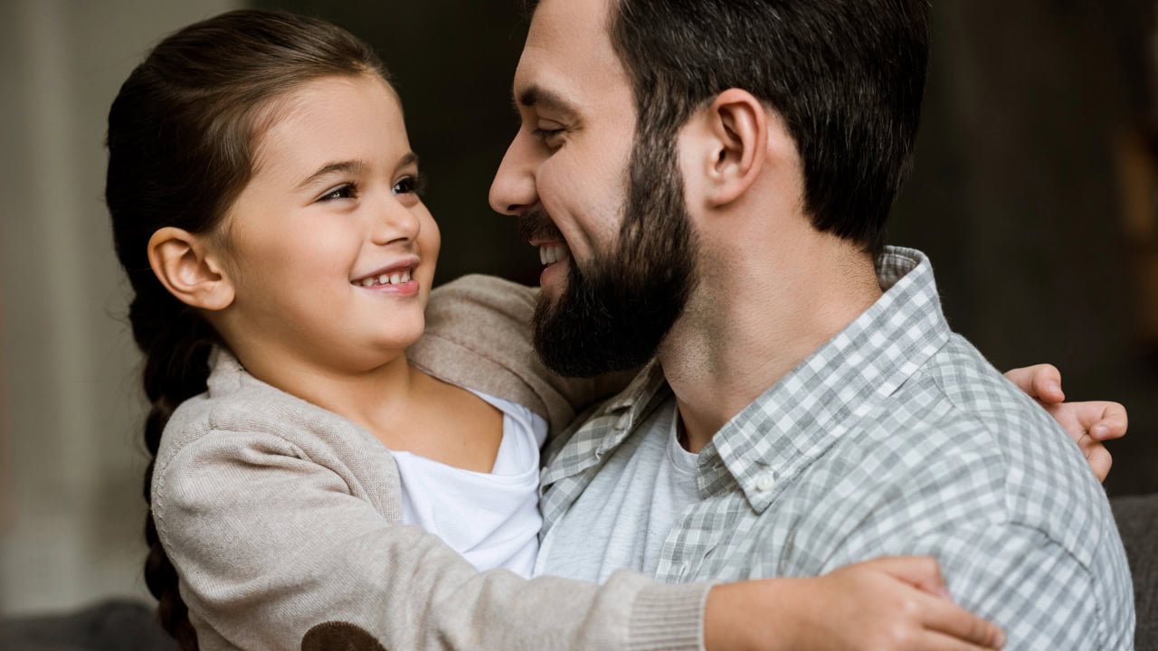 Father and daughter smiling and hugging. Image produced by More Jersey.