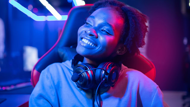 Female African American Streamer smiling in a neon color setting.