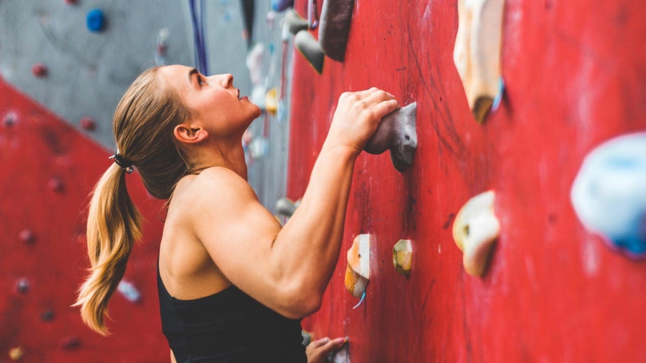 Female ascending indoor rock climbing wall at New Jersey indoor rock climbing gym.