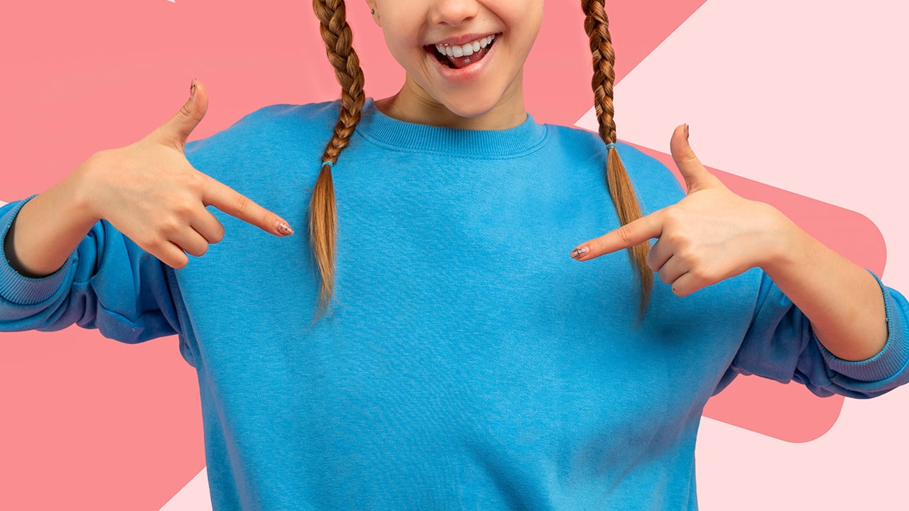 Girl with two braids pointing at herself. Image produced by More Jersey.