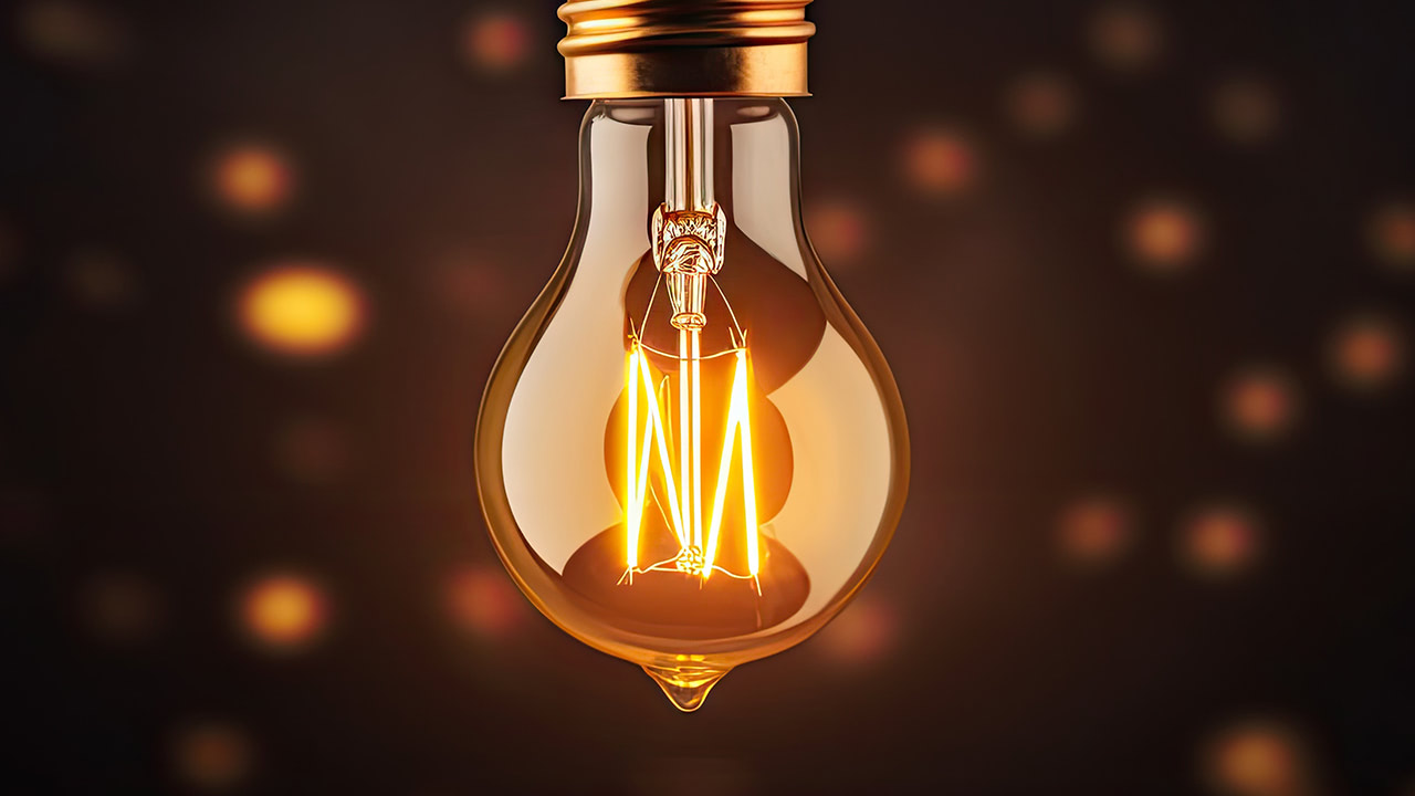 Glowing warm color vintage light bulb on brown background.