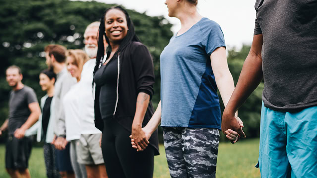 Group of diverse people holding hands at a local park.