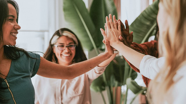 Group of diverse women high-fiving each other.