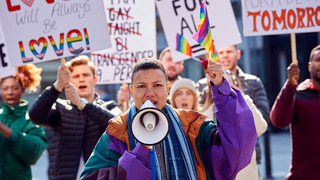 Group of LGBTQ+ protestors with placards and a megaphone fighting for gender equality.