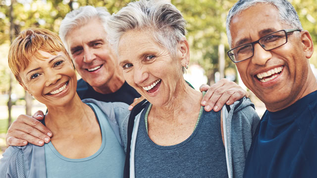 Group of senior residents smiling and taking a selfie at a local park.