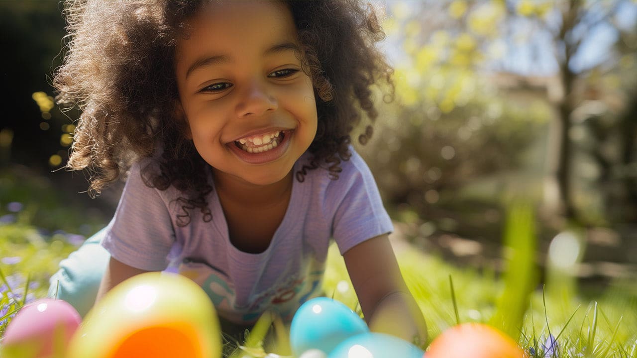 Happy African American child with a pile of plastic Easter egg hunt eggs.