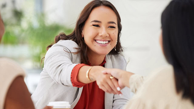 Happy diverse businesswomen shaking hands during business meeting.