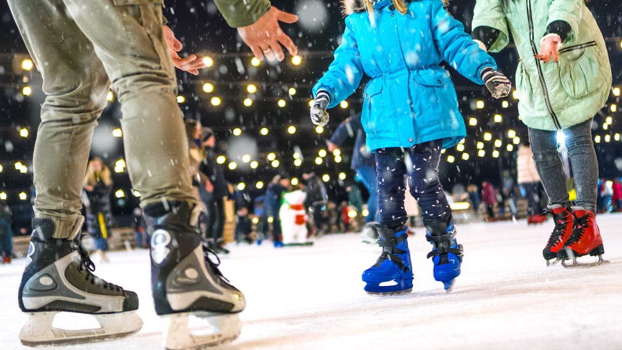 Happy family ice skating at outdoor New Jersey holiday winter event.