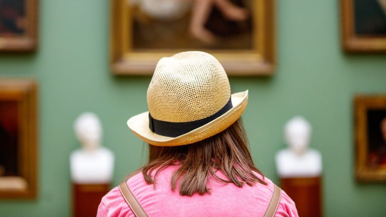 Lady wearing hat viewing paintings in a New Jersey museum.