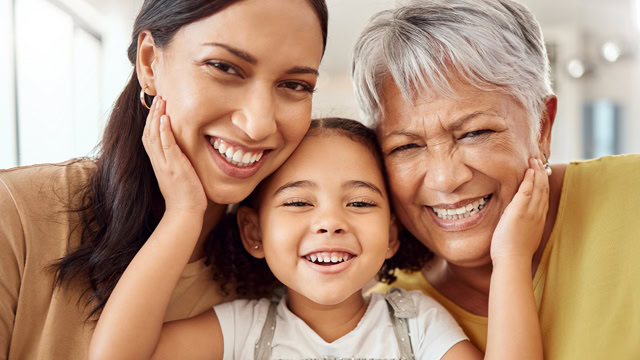 Latino daughter, mother, and grandmother smiling together.