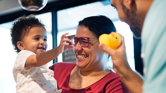 Latino parents playing with their daughter.